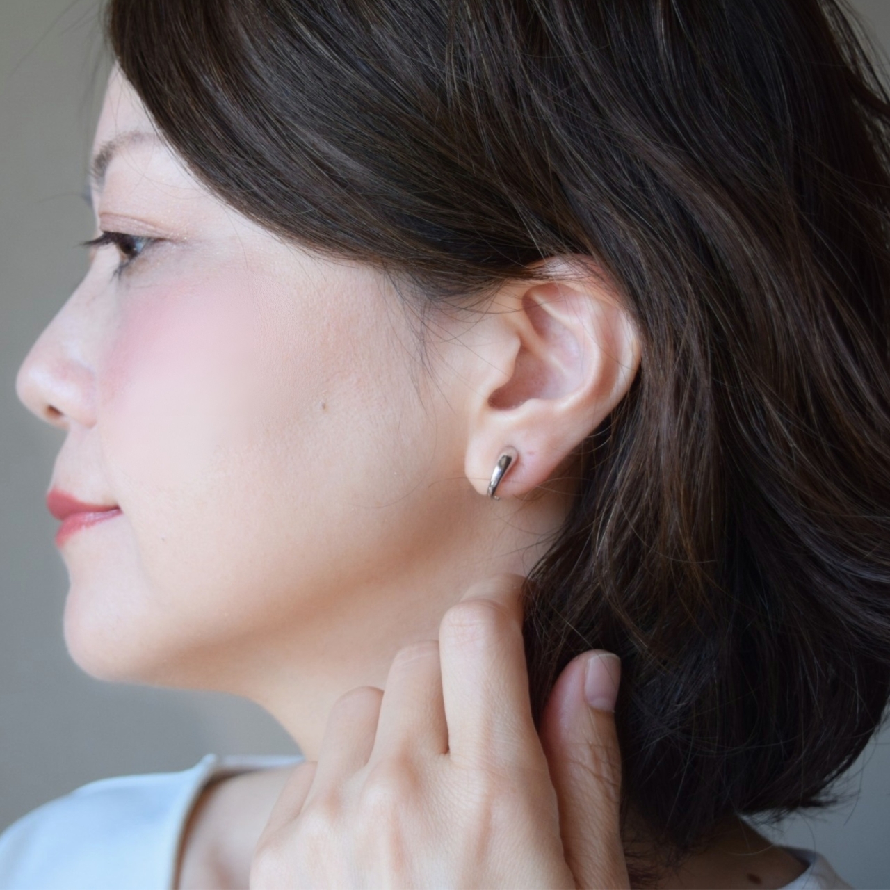 大人の女性の耳元に着用された、シルバー925製の地金イヤリング。無駄のないシルエットとシルバーの上品な輝きがモダンな印象を添え、ピアスのように軽やかに馴染んでいる様子。