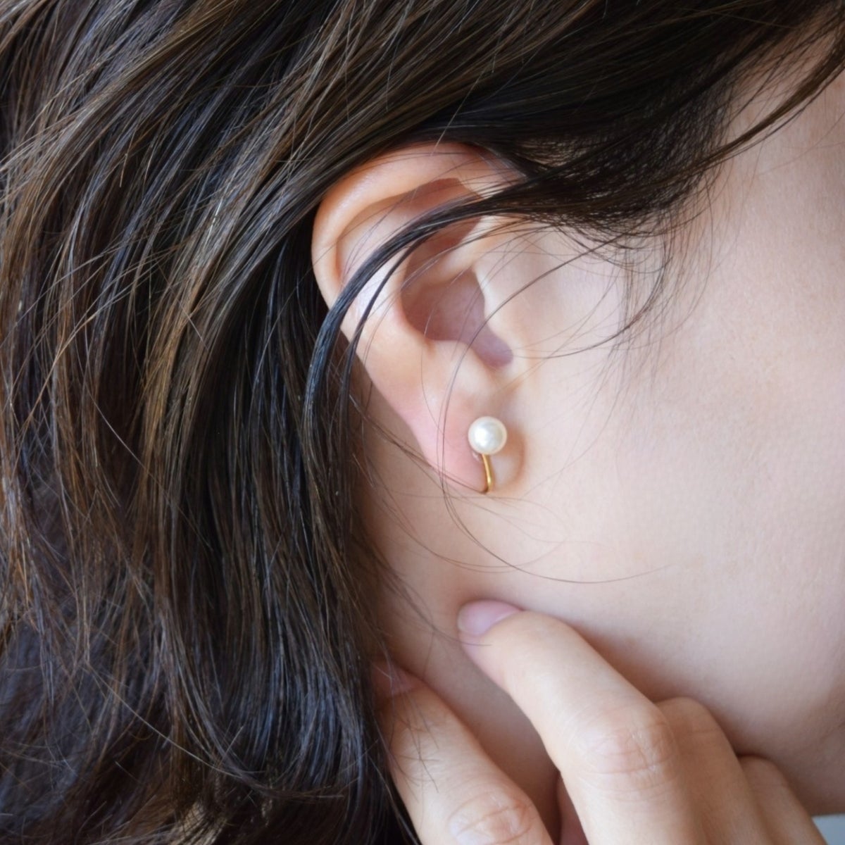 大人の女性の耳元に着用された、6mmの一粒ゴールドパールイヤリング。贅沢な金の艶とパールの輝きがお顔周りをパッと華やかにライトアップし、ピアスのように華奢に馴染んでいる様子。
