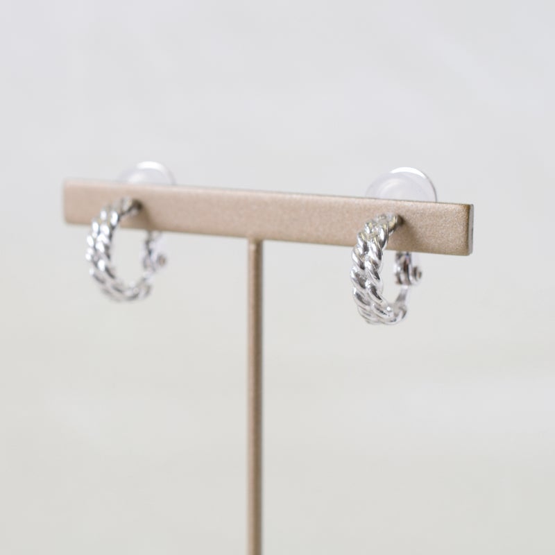 痛くないイヤリング Rope シルバー925製ツイストフープデザイン。ゴールドの什器にディスプレイされた、ピアス風のノンホールイヤリングの商品写真。